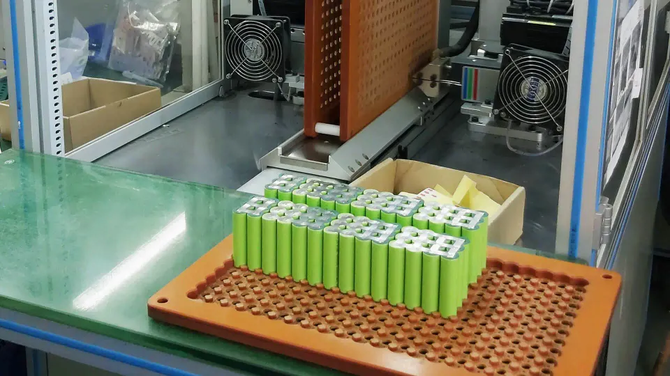 Lithium battery pack production fixture with green cell groups at a factory workstation